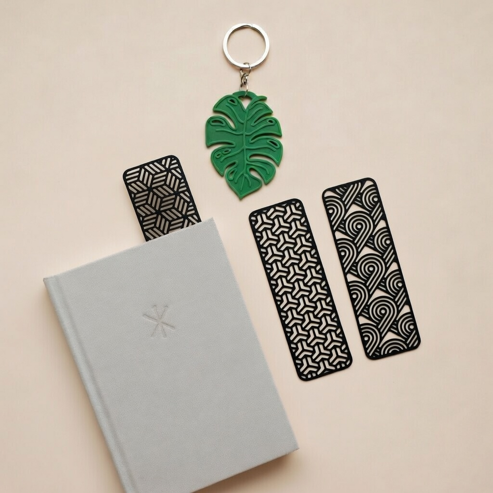 Book with black patterned bookmarks and a green leaf-shaped keychain on a beige background