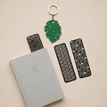 Book with black patterned bookmarks and a green leaf-shaped keychain on a beige background