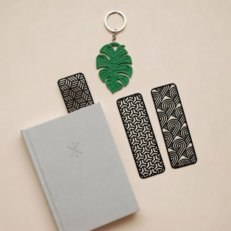 Book with black patterned bookmarks and a green leaf-shaped keychain on a beige background