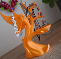 Orange tree-shaped jewelry holder with necklaces on a wooden surface.