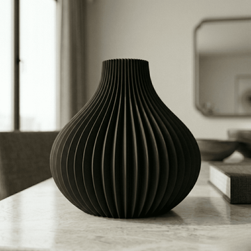 Black textured vase on a marble surface with a blurred background