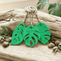 Green leaf-shaped keychains on a wooden surface with natural elements.