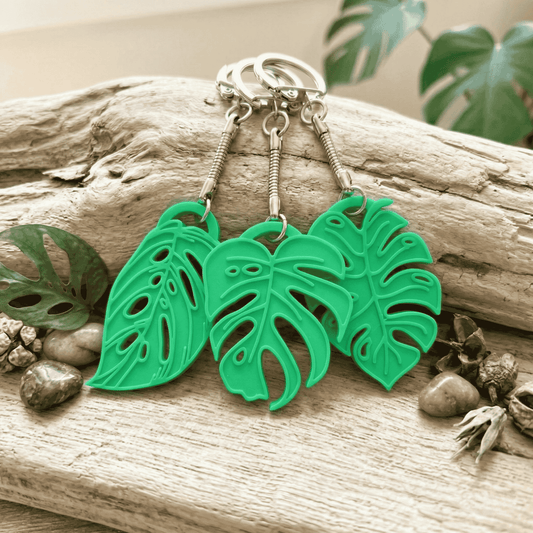 Green leaf-shaped keychains on a wooden surface with natural elements.