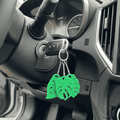 Green leaf-shaped keychain on a car key in a car's ignition.