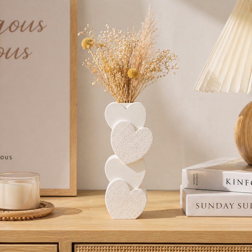 Decorative vase with heart design on a wooden surface with books and a candle.