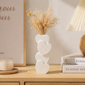 Decorative vase with heart design on a wooden surface with books and a candle.
