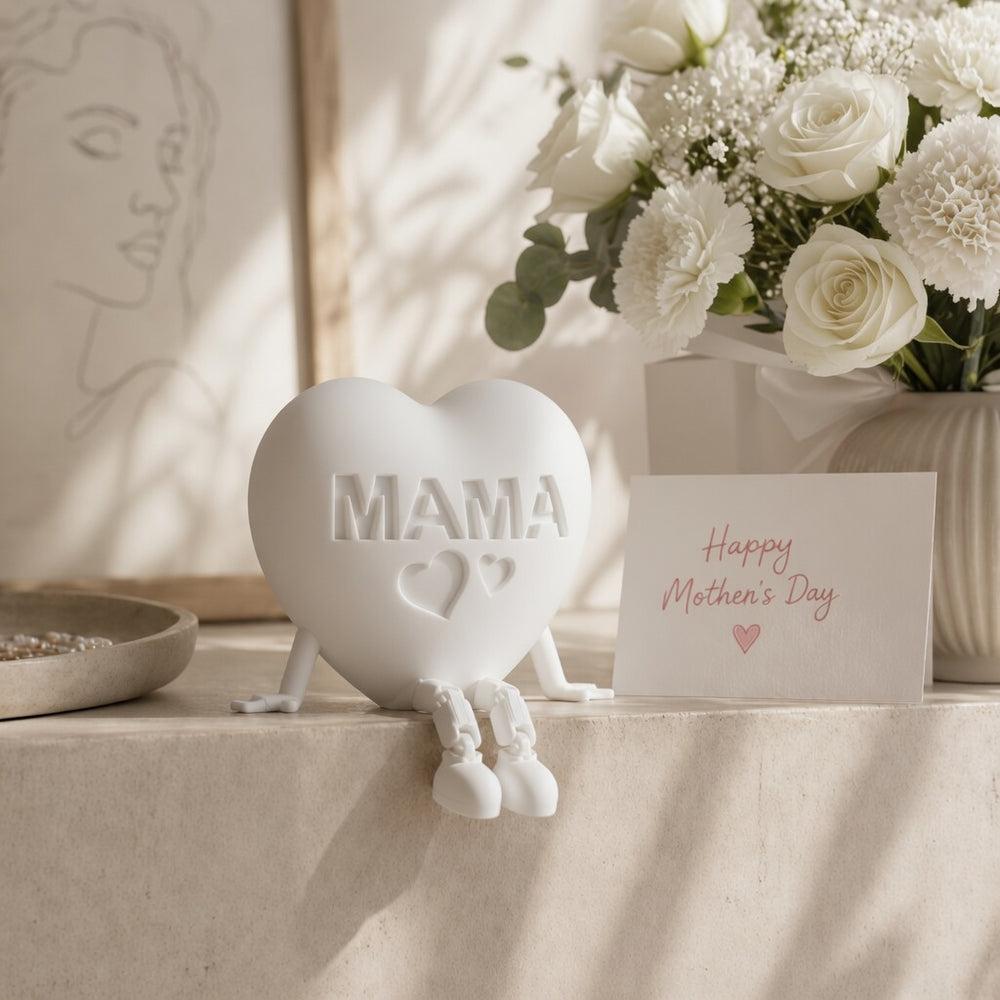 Heart-shaped 'MAMA' figurine with a 'Happy Mother's Day' card and flowers on a table.