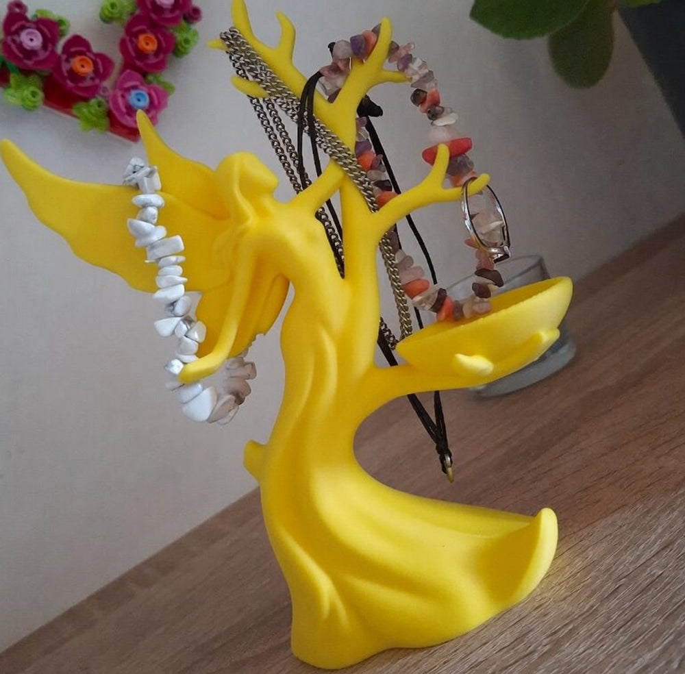 Yellow tree-shaped jewelry holder with necklaces on a wooden surface.