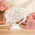 Decorative item with 'Mum' on a stand next to flowers and a candle, with a 'Happy Mother's Day!' card.