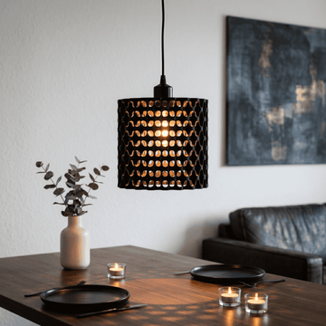 Modern pendant light hanging above a dining table with candles and a vase.