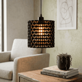 Modern pendant light hanging above a table with books and a plant in a living room setting.