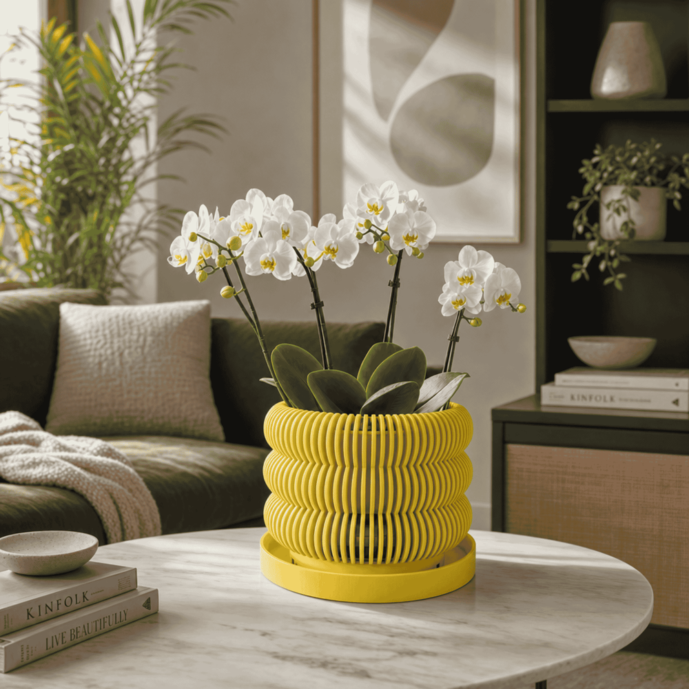 Yellow ribbed planter with white flowers on a marble table in a living room setting.